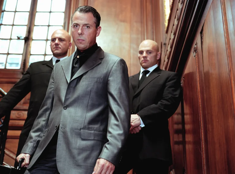 Three debt collectors in suits standing on a staircase